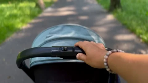 Close up of hand holding stroller handlebar on walk Stock Footage 337934813