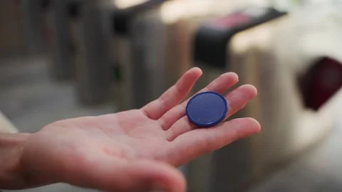 Close up hand holding subway token before entering turnstile Stock Footage 344845472