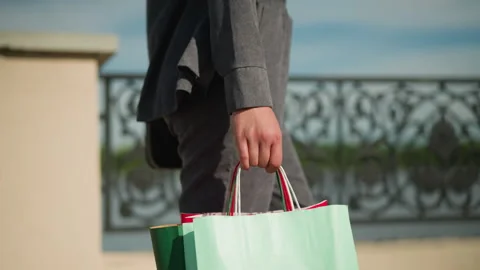 Close-up of Hand Holding Three Shopping Bags While Walking Near Fence Stock Footage 288948591