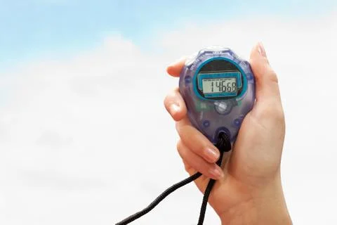 Close up of a hand holding a timer on a white background against blue sky wit Stock Photos
