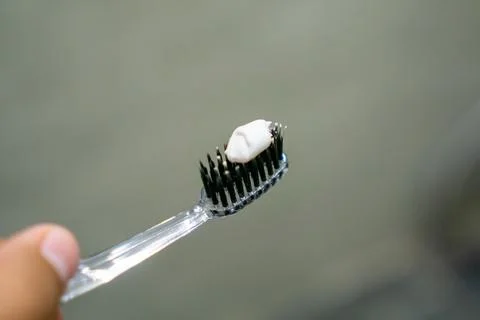 Close up of a hand holding a toothbrush with a toothpaste on the top. Oral .. Stock Photos