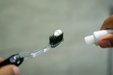 Close up of a hand holding a toothbrush with a toothpaste on the top. Oral .. Stock Photos