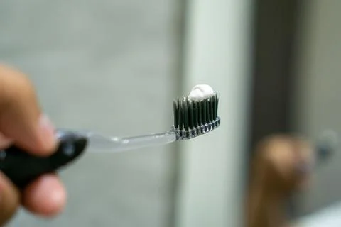 Close up of a hand holding a toothbrush with a toothpaste on the top. Oral .. Stock Photos