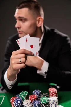 Close up of hand holding two aces playing cards in front of poker man Stock Photos