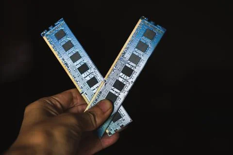 Close-up of a hand holding two blue computer RAM modules against a black ba.. 스톡 사진