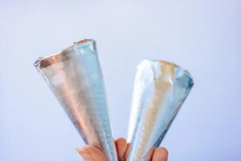 Close-up of a hand holding two empty metallic ice cream. Stock-Fotos