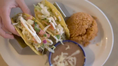 Close-up of a hand holding two tacos filled with fresh toppings, served with  Vidéo 276717826