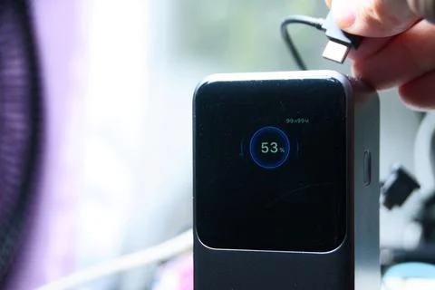 Close-up of a hand holding a USB-C cable plugged into a portable charger Stock-Fotos