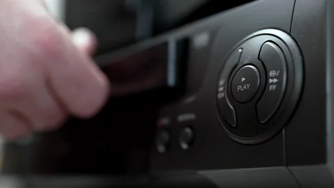 Close up of a hand holding a videotape. Retro vhs cassete in a player. Video stock 286426558
