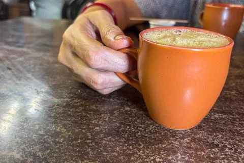 Close up of a Hand Holding Warm Coffee Cup on Rustic Table Stock Photos