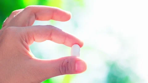 Close up hand holding white pill with fingers nature background Video stock 156238904