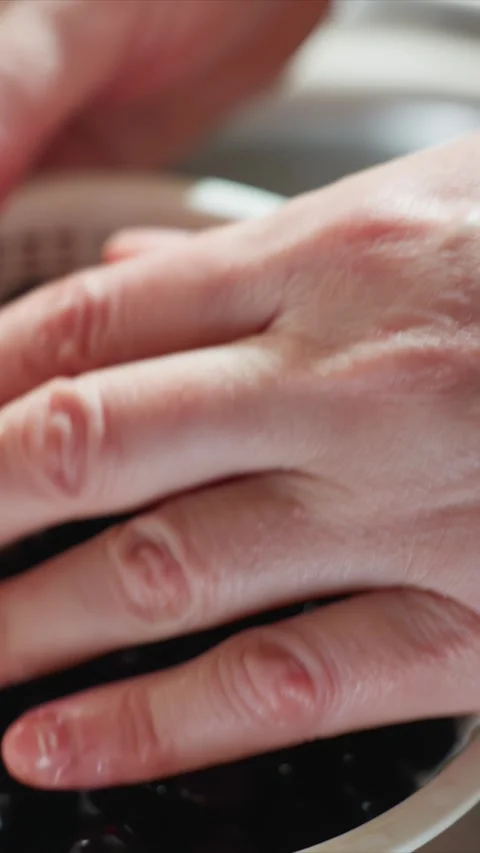 Close up of hand holding white plastic colander filled with wet shiny dark red Stock Footage 345669030