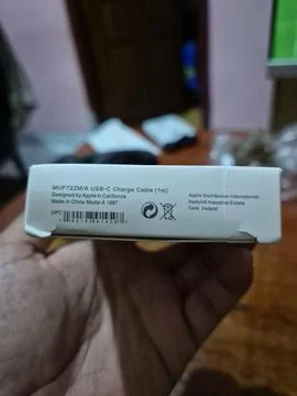 A close-up of a hand holding a white USB-C cable packaging box Stock Photos