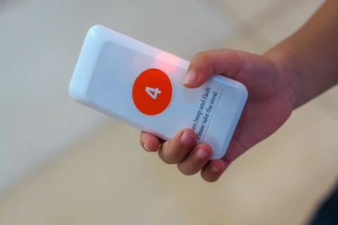 Close up of a hand holding a wireless queue calling system or wireless call.. Stock Photos