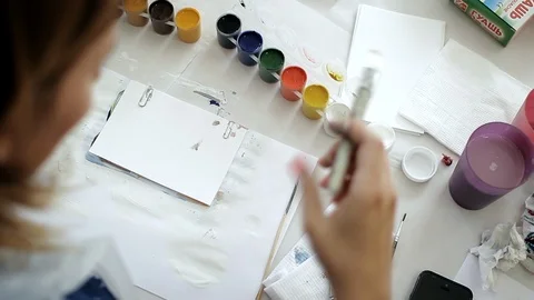 Close-up hand holds a brush, drawing with white paints on a sheet of paper. Stock Footage 115925543