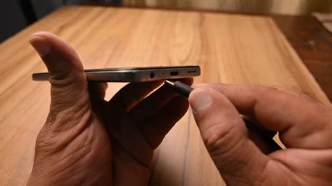 Close Up of Hand Inserting Charging Cable into Smartphone for Power Connection Stock Footage 333572350
