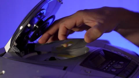 A close-up of a hand inserting a compact disc CD into the open tray of an o.. Stock Footage 315019585