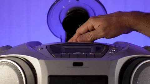 A close-up of a hand inserting a compact disc CD into the open tray of an o.. Stock Footage 315019604