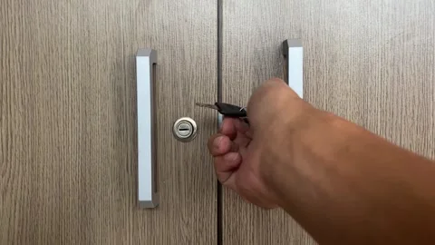 Close-up of Hand Inserting Key to Lock or Unlock Modern Office Cabinet Stock Footage 318574445