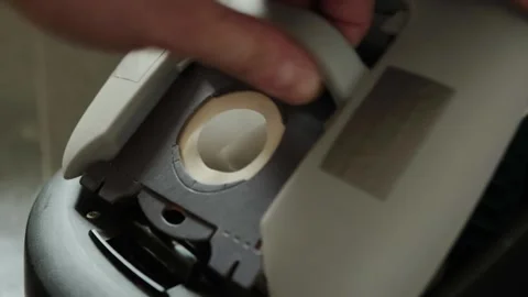Close-up of hand inserting new dust bag into vacuum cleaner compartment 库存影片 336246848