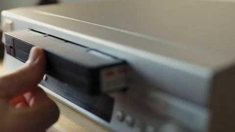 Close up of hand inserting tape into retro video recorder Stock Footage 347141387