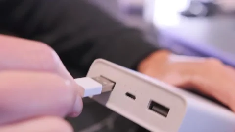 Close-up of hand inserting USB cable into power bank port for charging mobile Stock Footage 333650372