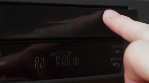 Close-up hand inserts a video cassette into the tray of the video player. s.. Stock Footage 234373551