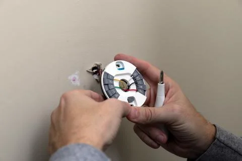 Close-up of Hand installing mounting plate for modern round thermostat for ai Stock Photos