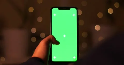 Close-up of a hand interacting with a green screen smartphone in a bokeh Stock Footage 339072038