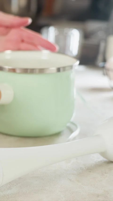 Close up of hand interacting with kitchen items including green mug pot and Stockbeeldmateriaal 344416285