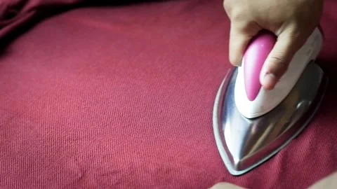Close-up of a hand ironing a red fabric Stock Footage 319544694