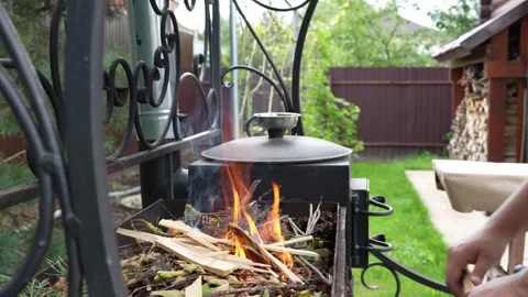 Close-up of a hand kindling a fire in a backyard grill Stock Footage 312100011