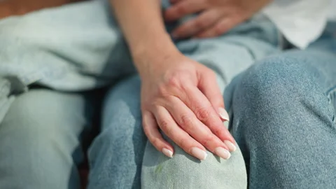 Close up hand on knee in blue denim with manicured nails and detailed fabric Stock Footage 346723120