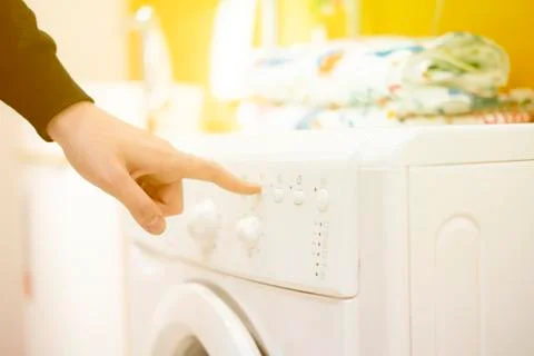 Close up hand launch set and start washing machine laundry at home bathroom Stock Photos