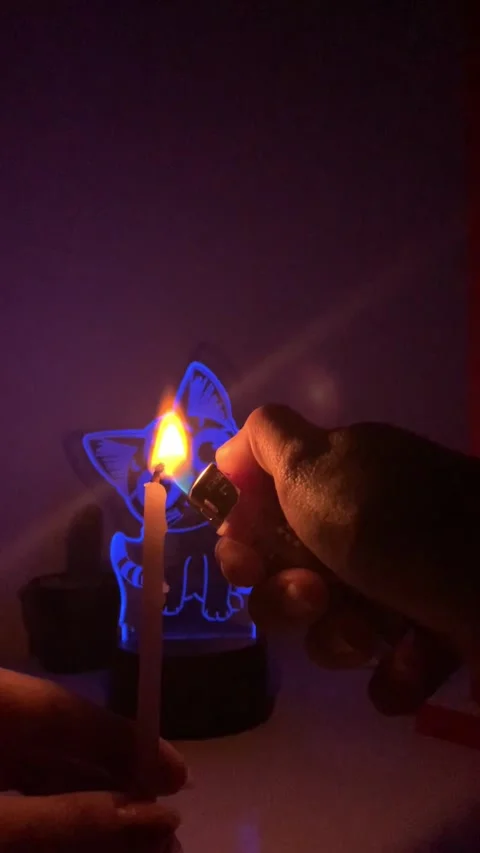 Close-up of a hand lighting a candle with a lighter in the dark, Vídeos de archivo 336849459
