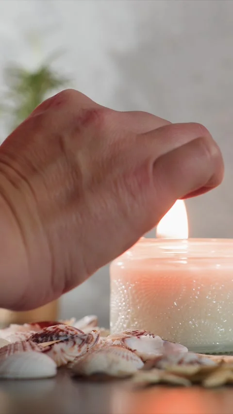 Close up hand lighting unscented candle with seashells on smooth textured Stock Footage 344682483