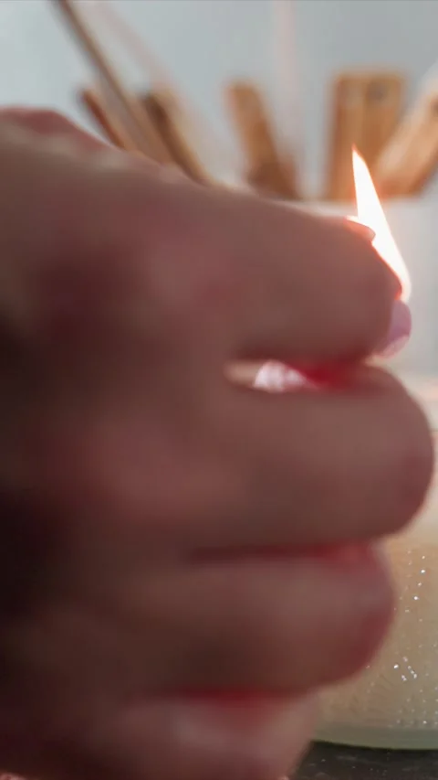 Close up hand lighting white textured candle with seashells and wooden sticks in Stock Footage 344671295