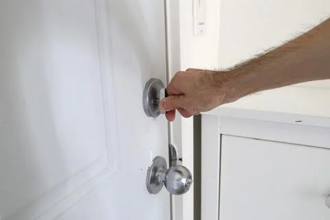Close up hand locking door with thumb turn metal lock home safety concept Stockfoto's