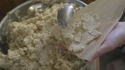 Close up hand makes tamale with masa on corn husk Stock Footage 251047172