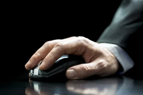 Close up of the hand of a man in a suit using a cordless computer mouse to .. Stock Photos