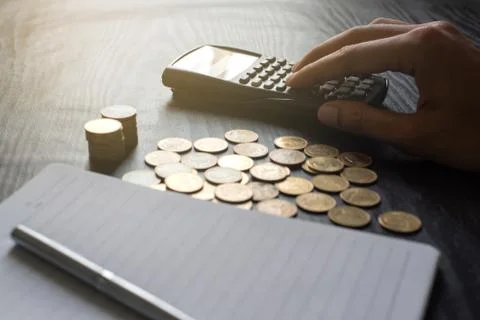 Close up hand of man using  calculator with gold coins, pen, notebook Stock Photos