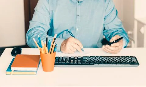 Close-up of hand man using a smartphone and typing on keyboard computer on wh Stock Photos