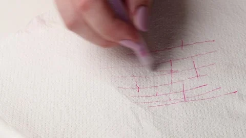 Close-up of a hand with manicured nails using a pen to draw random pink lines on Stock Footage 308013930