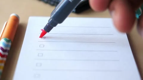 Close up of hand marking checklist items with red marker pen on paper. Stock Footage 332858321