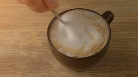 Close up of hand mixing cappuccino coffee foam with spoon Stock Footage 67512292