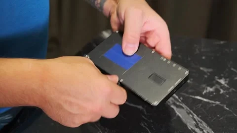 Close-up of hand mounting compact OLED light onto magic arm mount, attaching Stock Footage 333650148
