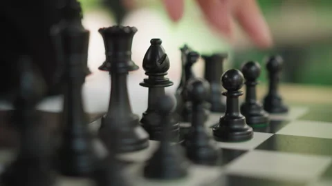 Close up of hand moving black chess pieces on checkered board with shallow depth Stock-Footage 346649460