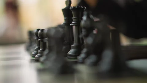 Close up hand moving black chess pawns with shallow depth focus and book Stock Footage 346649599