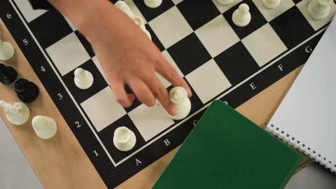 Close up of hand moving chess piece on board with green notebook nearby Stock-Footage 346650793