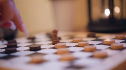 Close up hand moving chess pieces on checkered board with soft lighting and Stock-Footage 346729878